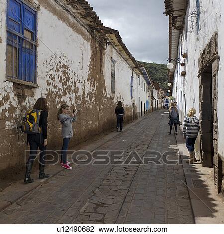 Stock Image - Girl taking picture of her sister in a street of Barrio de San Blas, Cuzco, Peru. Fotosearch