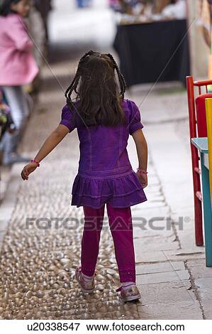 Stock Photo - Girl walking along a cobblestone sidewalk, Pisac, Sacred Valley, Cusco Region, Peru. Fotosearch