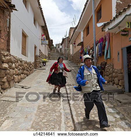 Stock Image - Man and woman running in a street, Sacred Valley, Cusco Region, Peru. Fotosearch