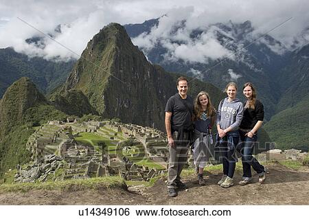 Stock Photograph - Man with his family with The Lost City of The Incas in the background, Machu Picchu, Cusco Region, Peru. Fotosearch
