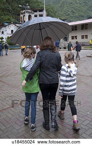 Mother with her daughters sheltering under an umbrella, Peru View Large Photo Image Picture - Mother with her daughters sheltering under an umbrella, Peru. Fotosearch
