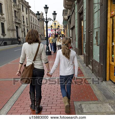 Stock Image - Rear view of a woman with her daughter walking in a street, Historic Centre of Lima, Lima, Peru. Fotosearch