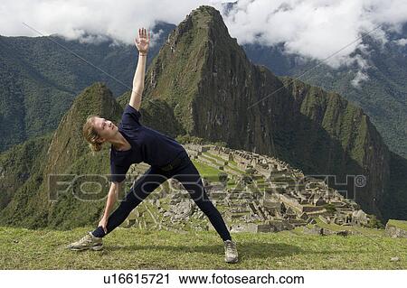 Stock Image - Teenage girl doing triangle pose with The Lost City of The Incas in the background, Machu Picchu, Cusco Region, Peru. Fotosearch