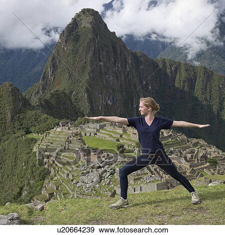Stock Photo - Teenage girl doing warrior 2 pose with The Lost City of The Incas in the background, Machu Picchu, Cusco Region, Peru. Fotosearch