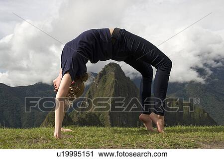 Stock Image - Teenage girl doing wheel pose with valley in the background, The Lost City of The Incas, Machu Picchu, Cusco Region, Peru. Fotosearch