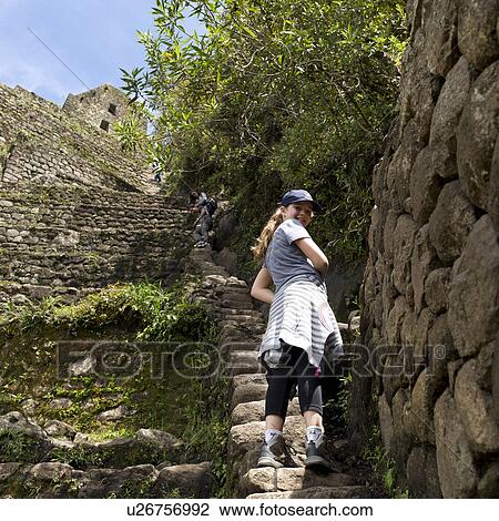 Stock Image - Teenage girl standing on steps at The Lost City of The Incas, Machu Picchu, Cusco Region, Peru. Fotosearch