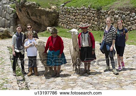 Stock Photograph - Tourists and a Peruvian woman standing with a llama and alpaca, Sacsayhuaman, Cuzco, Peru. Fotosearch