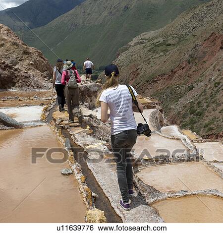 Stock Photograph - Tourists at a salt mine, Maras, Salinas, Sacred Valley, Cusco Region, Peru. Fotosearch