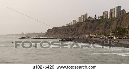 Stock Photograph - Tourists on the beach with a city in the background, Miraflores District, Lima Province, Peru. Fotosearch