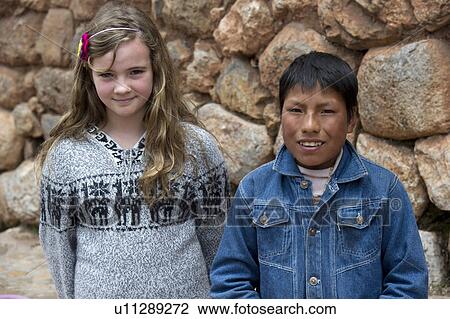 Stock Image - Two friends standing in front of a stone wall, Sacred Valley, Cusco Region, Peru. Fotosearch