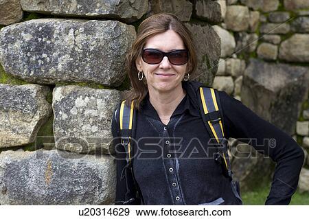 Stock Photo - Woman leaning against a stone wall at The Lost City of The Incas, Machu Picchu, Cusco Region, Peru. Fotosearch