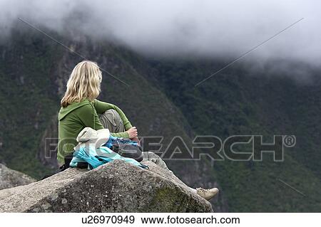 Stock Photo - Woman sitting on a stone at The Lost City of The Incas, Machu Picchu, Cusco Region, Peru. Fotosearch