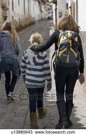 Stock Image - Woman with her daughters walking in a street of Barrio de San Blas, Cuzco, Peru. Fotosearch