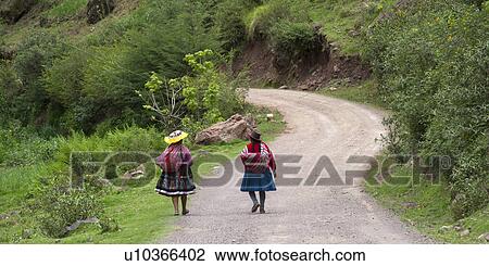 Stock Image - Women walking on a dirt road, Sacred Valley, Cusco Region, Peru. Fotosearch