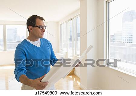 Stock Photo - Architect reading blueprint in new office. Fotosearch