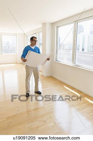 Stock Photography - Architect reading blueprint in new office. Fotosearch