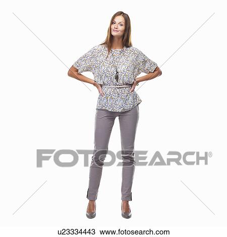 Stock Image - Beautiful smiling woman standing with hands on hips against white background. Fotosearch