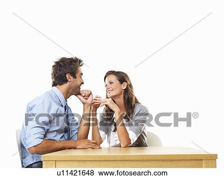 Business couple sitting at table with hands close to each other and smiling View Large Photo Image Stock Photo - Business couple sitting at table with hands close to each other and smiling. Fotosearch