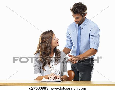 Stock Image - Business woman and business man reading document together. Fotosearch