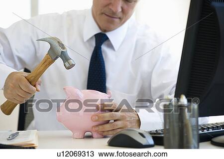 Businessman hammering piggy bank View Large Photo Image Stock Image - Businessman hammering piggy bank. Fotosearch