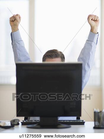 Businessman raising hands from behind computer View Large Photo Image Stock Photo - Businessman raising hands from behind computer. Fotosearch