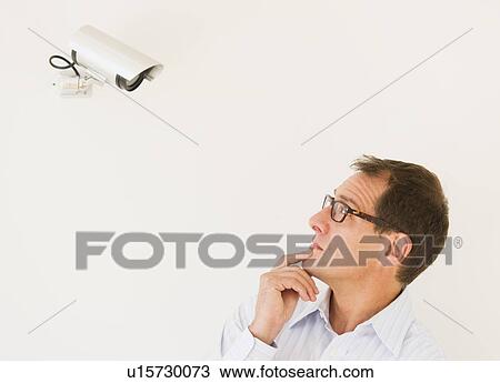 Businessman under surveillance of security camera View Large Photo Image Stock Image - Businessman under surveillance of security camera. Fotosearch