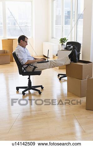 Stock Photo - Businessman using laptop in new office. Fotosearch