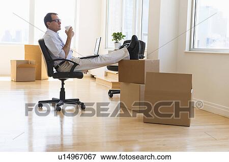 Stock Photo - Businessman using laptop in new office. Fotosearch
