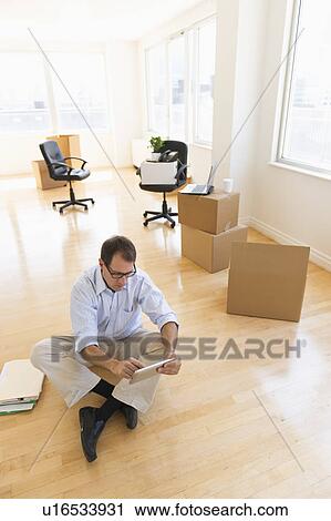 Stock Image - Businessman using tablet in new office. Fotosearch