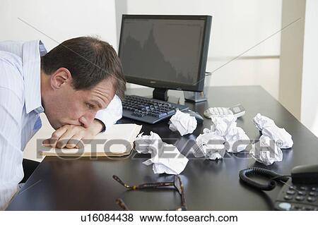 Stock Photo - Businessman with face down on desk. Fotosearch