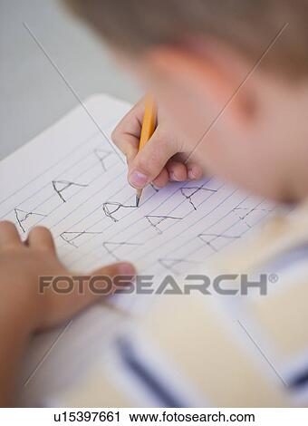 Stock Image - Close up of boy (4-5) writing in notebook. Fotosearch