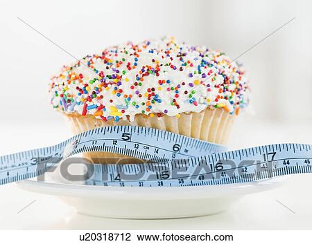 Stock Image - Close up of cupcake with measuring tape. Fotosearch