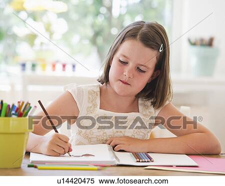 Stock Photography - Close up of girl (6-7) drawing in notebook. Fotosearch