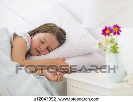 Stock Image - Close up of girl (6-7) sleeping in bed. Fotosearch