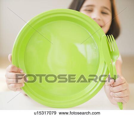 Stock Photo - Close up of girl (8-9) with green plate. Fotosearch