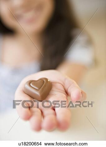 Picture - Close up of girl's (10-11) hand holding chocolate heart. Fotosearch