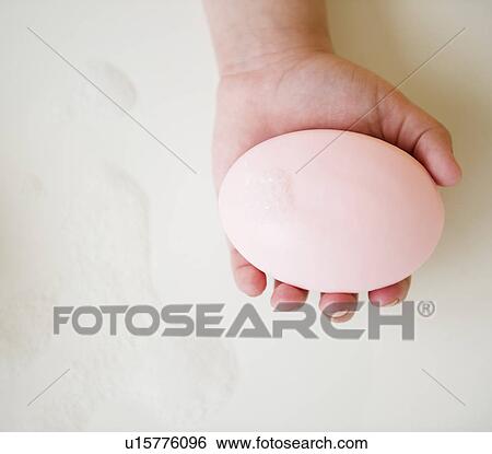 Stock Photograph - Close up of girl's (8-9) hand holding soap bar. Fotosearch