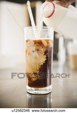 Close up of hand pouring milk into iced coffee View Large Photo Image Stock Photograph - Close up of hand pouring milk into iced coffee. Fotosearch