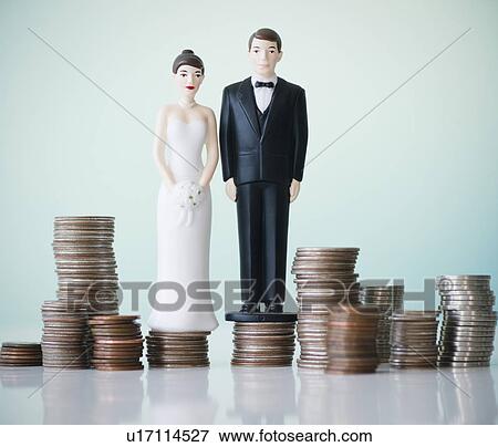 Close up of wedding cake figurines on stacks of coins View Large Photo Image Stock Photo - Close up of wedding cake figurines on stacks of coins. Fotosearch