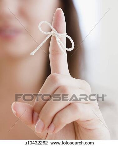 Stock Image - Close up of woman's finger with tied knot. Fotosearch