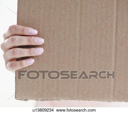 Picture - Close up of woman's hand holding cardboard. Fotosearch