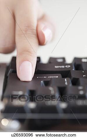 Stock Photograph - Close up of woman's hand pressing enter key. Fotosearch
