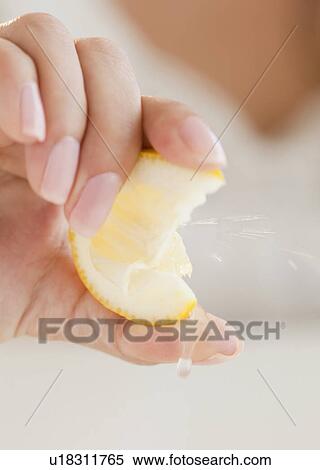 Stock Photography - Close up of woman's hand squeezing lemon. Fotosearch