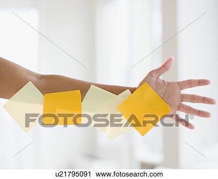 Stock Image - Close up of woman's hand with adhesive notes. Fotosearch