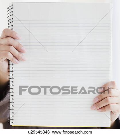 Stock Image - Close up of woman's hands holding blank notebook. Fotosearch