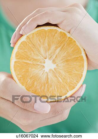 Close up of woman's hands holding half of orange View Large Photo Image Picture - Close up of woman's hands holding half of orange. Fotosearch