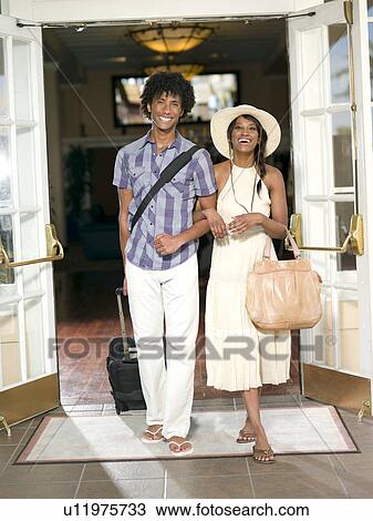 Couple exiting hotel with their luggage View Large Photo Image Stock Image - Couple exiting hotel with their luggage . Fotosearch