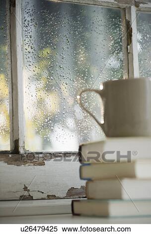 Cup on heap of books with rain on window in background View Large Photo Image Stock Photography - Cup on heap of books with rain on window in background. Fotosearch