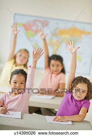 Stock Photograph - Four girls (6-9) raising hands in classroom. Fotosearch