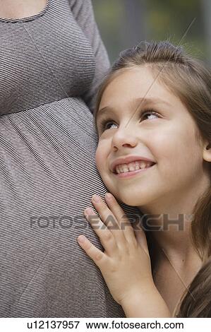 Stock Photo - Girl (6-7) pregnant mother's belly. Fotosearch
